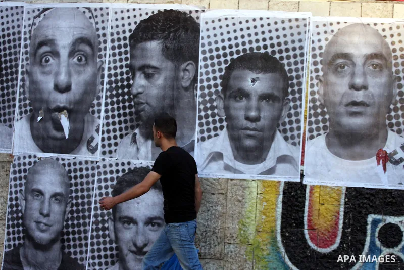 A Palestinian man walks past large black and white photographs taken by French street artist JR of Palestinians, on September 6, 2011, in the West Bank city of Ramallah. JR's project entails having Palestinian and Israel...