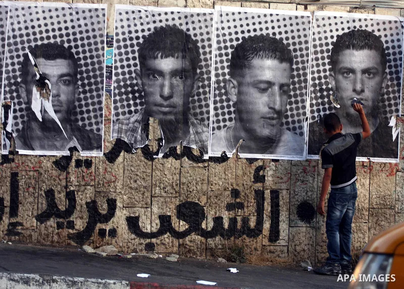 A Palestinian man walks past large black and white photographs taken by French street artist JR of Palestinians, on September 6, 2011, in the West Bank city of Ramallah. JR's project entails having Palestinian and Israel...