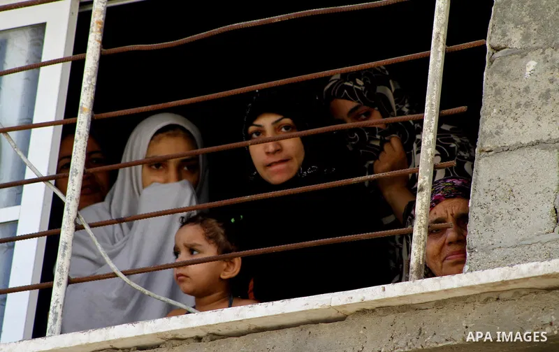 Palestinian women look through a window at the funeral procession of the member of its military wing the Al-Quds Brigades, Remah al-Hasani, in Gaza city on Sep. 8, 2011. He was killed as he was driving in the central Dei...