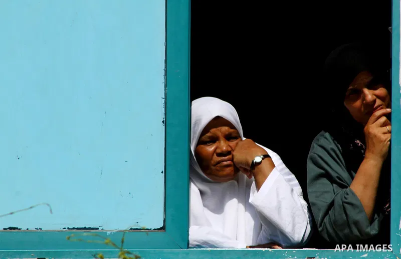 Palestinian women look through a window at the funeral procession of the member of its military wing the Al-Quds Brigades, Remah al-Hasani, in Gaza city on Sep. 8, 2011. He was killed as he was driving in the central Dei...