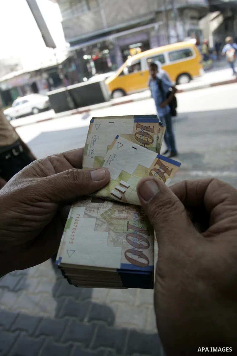 A Palestinian man exchanges currency, in the in city of Rafah the southern Gaza Strip, the U.S. dollar and shekel in black markets in the Gaza Strip on Sep. 8, 2011. Significant increase to the U.S. dollar $1000 against...