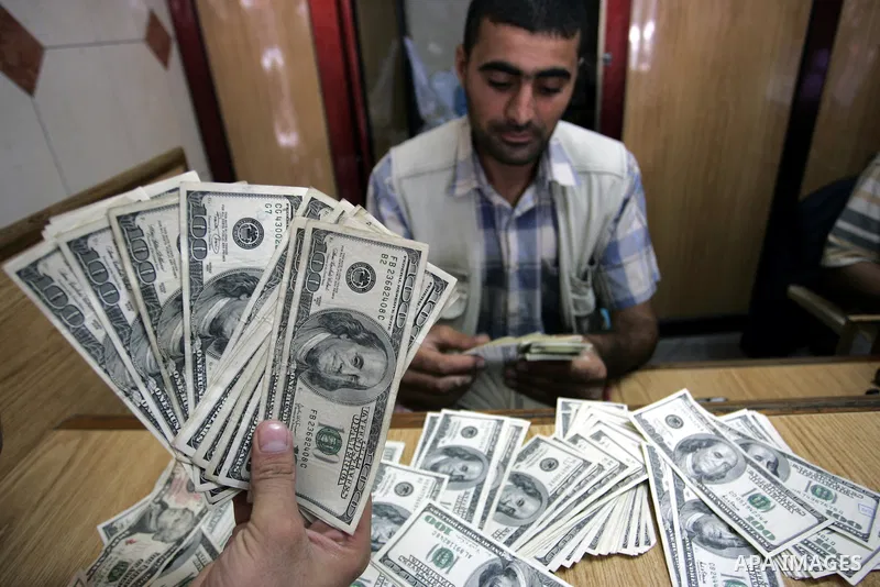 A Palestinian man exchanges currency, in the in city of Rafah the southern Gaza Strip, the U.S. dollar and shekel in black markets in the Gaza Strip on Sep. 8, 2011. Significant increase to the U.S. dollar $1000 against...