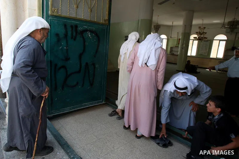 Palestinians attend praying at a mosque whose door was vandalized with the Hebrew words "PR (Price Tag) Migron" in the northern West Bank village of Yatma, Thursday, Sept. 8, 2011. Israeli West Bank settlers, meanwhile,...