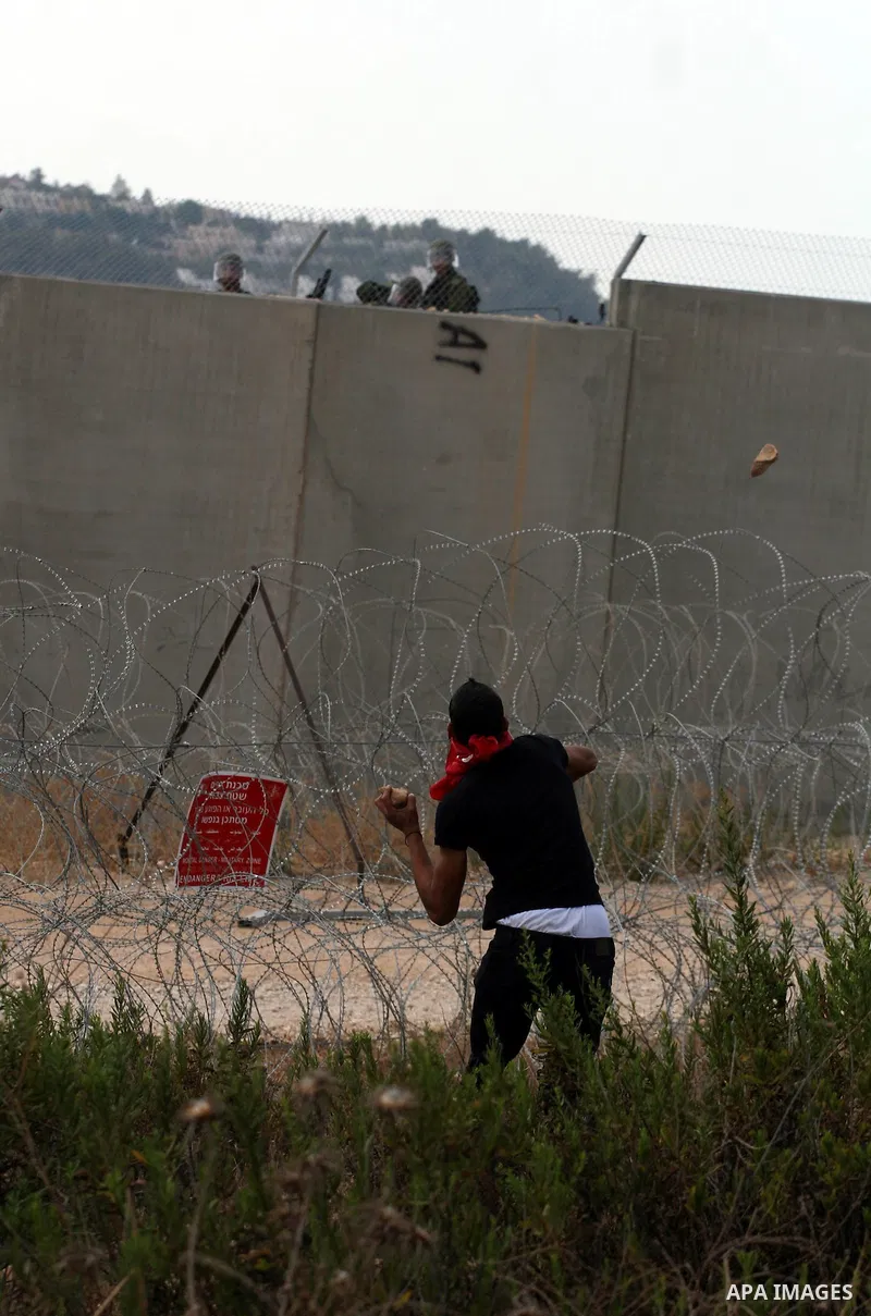A Palestinian man hurls stones toward Israeli soldiers during a demonstration in the West Bank town of Bilin, near Ramallah, Friday, Sept. 9, 2011. The Palestinians have launched a campaign to rally support for U.N. reco...