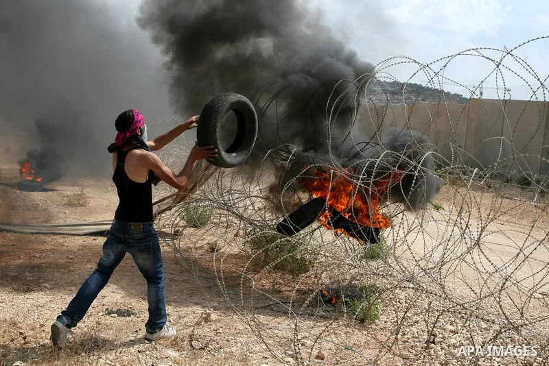 A Palestinian protester throws a tyre towards part of the controversial Israeli barrier during a demonstration in the West Bank town of Bilin, near Ramallah, Friday, Sept. 9, 2011. The Palestinians have launched a campai...