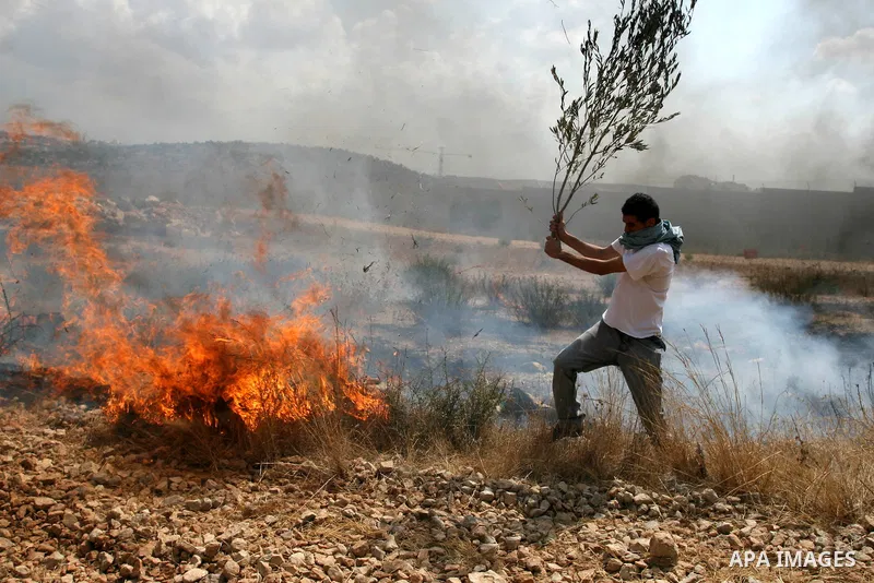 A Palestinian man tries to extinguish a fire ignited by a teargas grenade during a demonstration in the West Bank town of Bilin, near Ramallah, Friday, Sept. 9, 2011. The Palestinians have launched a campaign to rally su...