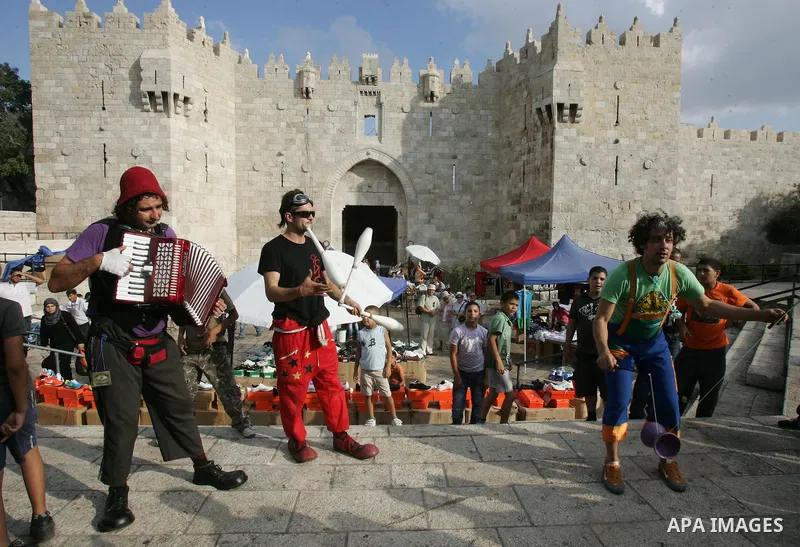 Performers with the international "Festiclown" group entertain passers-by outside Damascus Gate in Jerusalem's Old City on September 9, 2011, as part of the first international clown festival in the Palestinian territori...