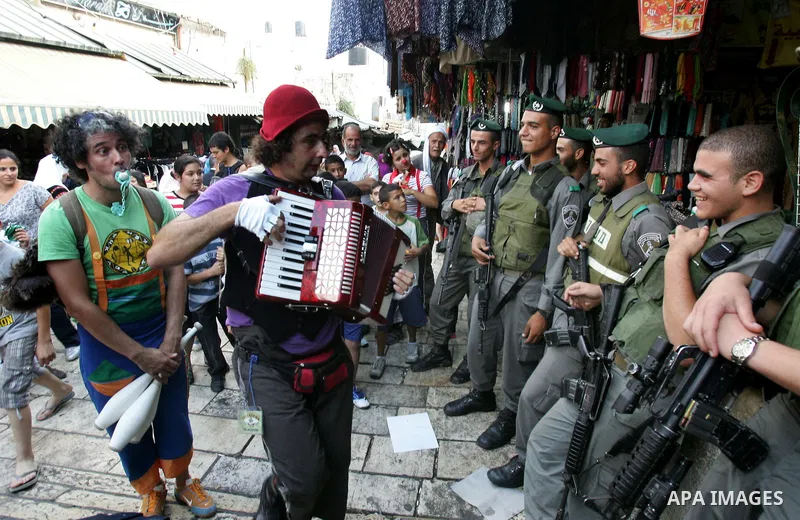 Israeli soldiers look at performers with the international "Festiclown" group as they entertain passers-by near Damascus Gate in Jerusalem's Old City on September 9, 2011, as part of the first international clown festiva...