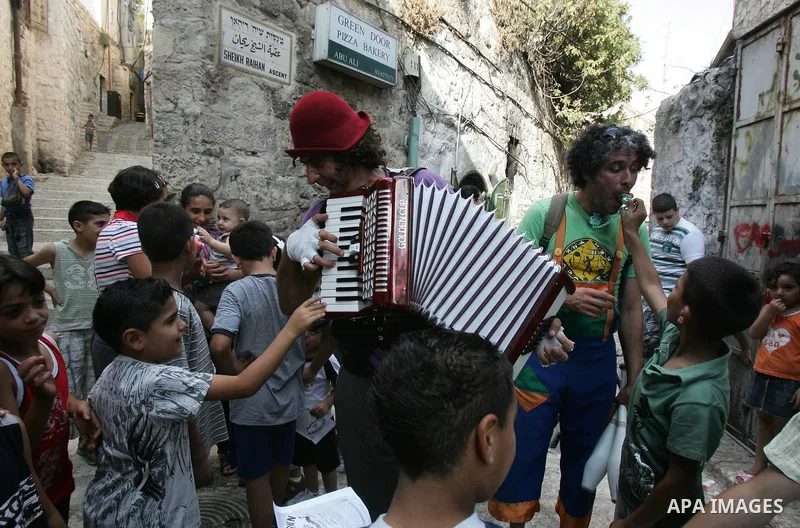 Performers with the international "Festiclown" group entertain passers-by outside Damascus Gate in Jerusalem's Old City on September 9, 2011, as part of the first international clown festival in the Palestinian territori...