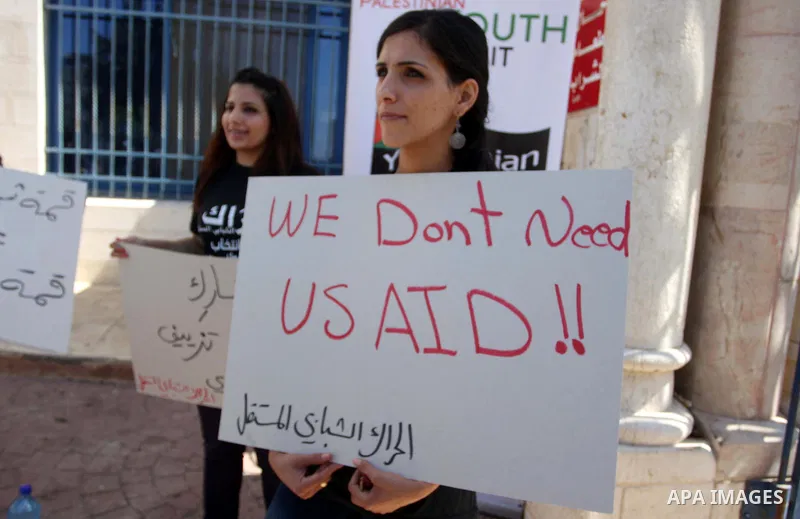 Palestinian youths hold placards bearing anti US and USAID slogans during a protest against United States policies in regard to the Palestinian-israeli conflict in the West Bank city of Ramallah on September 10, 2011. Ph...