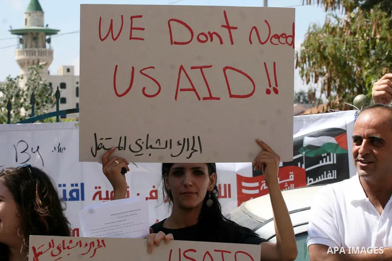 Palestinian youths hold placards bearing anti US and USAID slogans during a protest against United States policies in regard to the Palestinian-israeli conflict in the West Bank city of Ramallah on September 10, 2011. Ph...