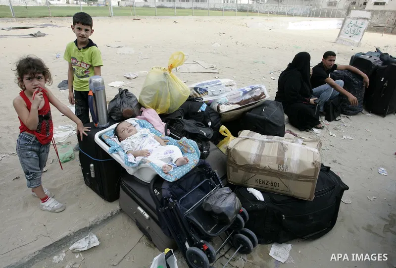 Palestinians sit near their luggage as they wait to cross into Egypt through the Rafah border crossing in the southern Gaza Strip on Sep 12, 2011. Photo by Abed Rahim Khatib