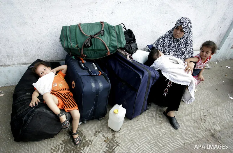 Palestinians sit near their luggage as they wait to cross into Egypt through the Rafah border crossing in the southern Gaza Strip on Sep 12, 2011. Photo by Abed Rahim Khatib