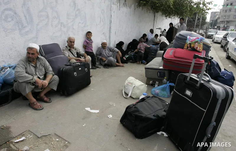 Palestinians sit near their luggage as they wait to cross into Egypt through the Rafah border crossing in the southern Gaza Strip on Sep 12, 2011. Photo by Abed Rahim Khatib