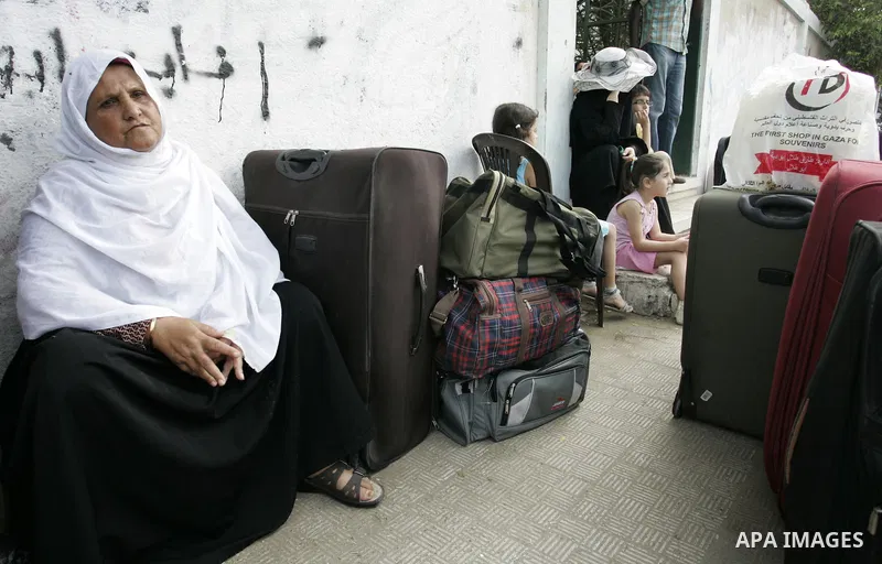 Palestinians sit near their luggage as they wait to cross into Egypt through the Rafah border crossing in the southern Gaza Strip on Sep 12, 2011. Photo by Abed Rahim Khatib