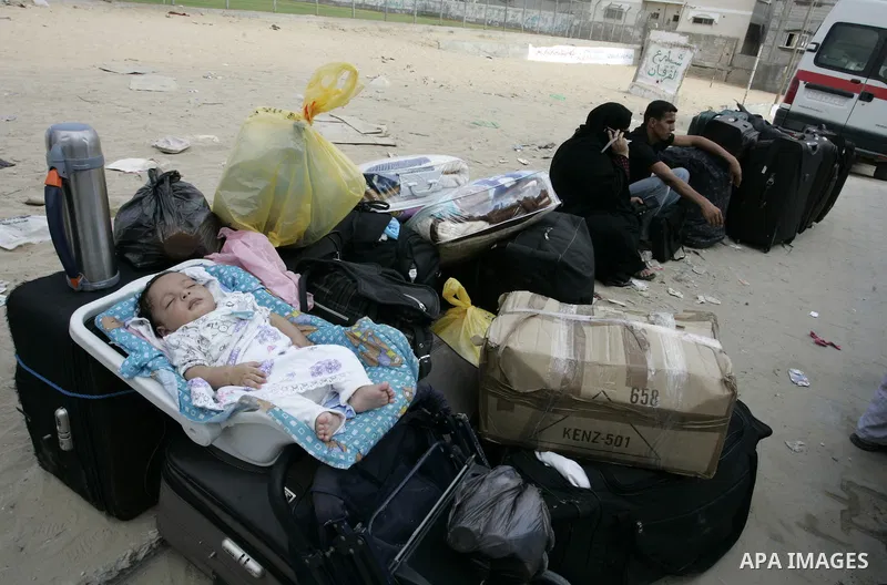 Palestinians sit near their luggage as they wait to cross into Egypt through the Rafah border crossing in the southern Gaza Strip on Sep 12, 2011. Photo by Abed Rahim Khatib