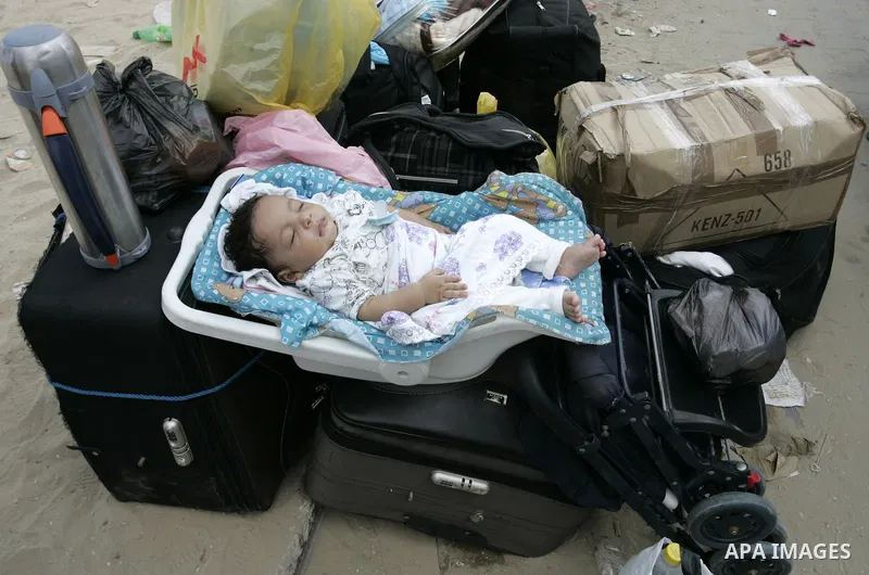 A Palestinian baby sleep on the family luggage as they wait to cross into Egypt through the Rafah border crossing in the southern Gaza Strip on Sep 12, 2011. Photo by Abed Rahim Khatib