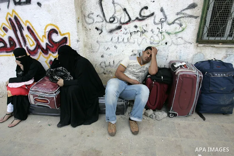 Palestinians sit near their luggage as they wait to cross into Egypt through the Rafah border crossing in the southern Gaza Strip on Sep 12, 2011. Photo by Abed Rahim Khatib