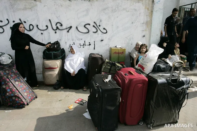 Palestinians sit near their luggage as they wait to cross into Egypt through the Rafah border crossing in the southern Gaza Strip on Sep 12, 2011. Photo by Abed Rahim Khatib