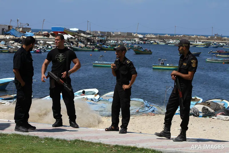 Palestinian policemen stand while the students hold the pictures of Turkish Prime Minister Recep Tayyip Erdogan and the Turkish and Palestinian flags during rally beckoning him to visit the Gaza Strip at the port in Gaza...