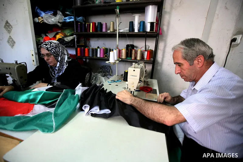 Palestinian Nabil al-Saed and his wife Nabila make Palestinian flags in a factory in the West Bank city of Hebron on 13 September 2011. According to Nabil al-Saed, with the Palestinian push for recognition of statehood a...