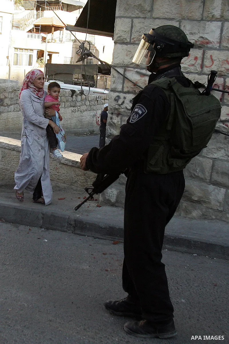 A Palestinian woman walks past Israeli riot policeman standing guard in the east Jerusalem neighborhood of Silwan on Sep. 13, 2011 following brief clashes between police and Palestinian stone throwers. Photo by Mahfouz A...
