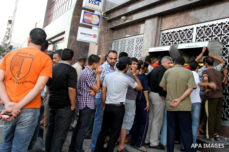 Palestinian Authority civil servants gather outside the Arab Bank in Gaza city on Sep. 13,2011, to withdraw their monthly salaries which were delayed for ten days from the begining of the new month. Photo by Mohammed Asa...