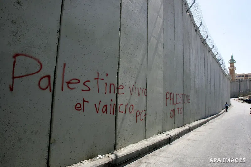 Palestinians walk past a section of Israel's controversial concrete barrier that separates the West Bank from Jerusalem on September 14, 2011. in Abu Dis, in Israeli-annexed east Jerusalem. Photo by Mahfouz Abu Turk