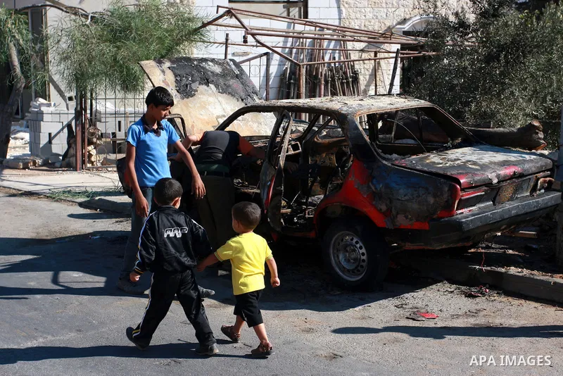Palestinians walk next to a burnt car in the village of Beit Furik, near the West Bank town of Nablus, on Sept. 15, 2011. Vandals set fire to three cars in a West Bank village, and suspicion has fallen on Jewish settlers...