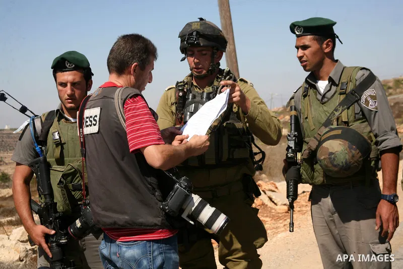 Israeli soldiers speak with a photographer as Palestinian and international activists work on a Palestinian's farm land in the West Bank village of Beit Omar near Hebron, 16 September 2011. The Israeli soldiers eventuall...