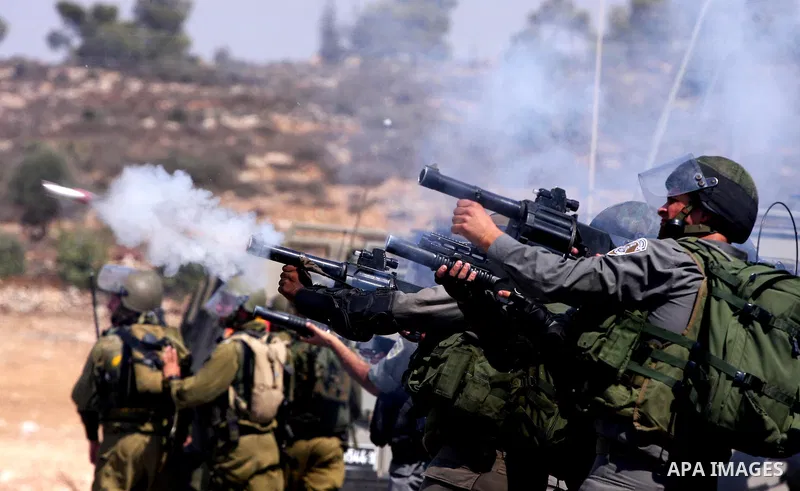 Israeli soldiers shoot tear gas canisters toward Palestinian demonstrators during a protest against the expansion of the nearby Jewish settlement of Halamish, in the West Bank village of Nabi Saleh, near Ramallah, Friday...