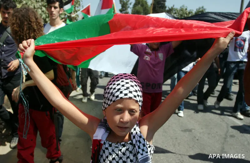 Palestinian demonstrators and international activists wave with Palestinian flag during a protest against the expansion of the nearby Jewish settlement of Halamish, in the West Bank village of Nabi Saleh, near Ramallah,...