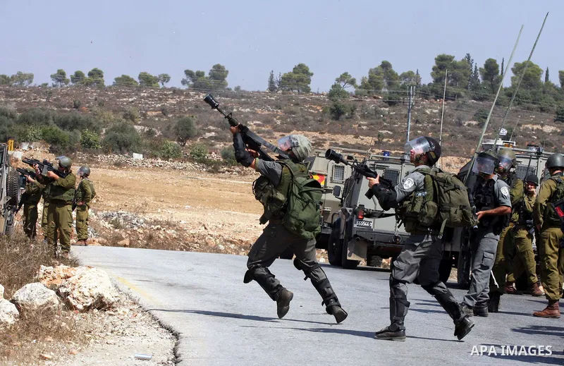 Israeli soldiers shoot tear gas canisters toward Palestinian demonstrators during a protest against the expansion of the nearby Jewish settlement of Halamish, in the West Bank village of Nabi Saleh, near Ramallah, Friday...