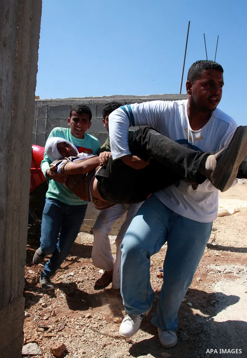Palestinians help a man who was hit by a rubber bullet during clashes with Israeli troops at Qusra village near the West Bank city of Nablus on 16 September 2011. Israeli settlers assaulted the village Friday morning, le...