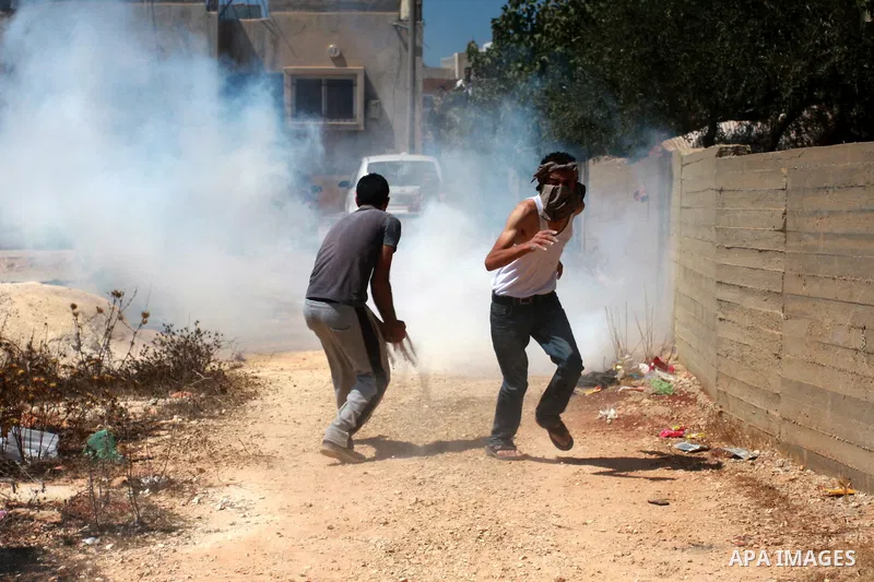 Palestinians take cover from tear gas during clashes at Qusra village near the West Bank city of Nablus on 16 September 2011. Israeli settlers assaulted the village Friday morning, leading to clashes with Israeli forces...