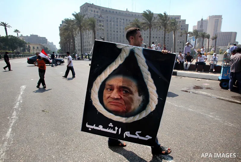 An Egyptian youth holds a poster showing former Egyptian President Hosni Mubarak on a noose at Tahrir Square while hundreds of Egyptians demonstrate against the expansion of the Emergency Law at Al Tahrir Square. The law...