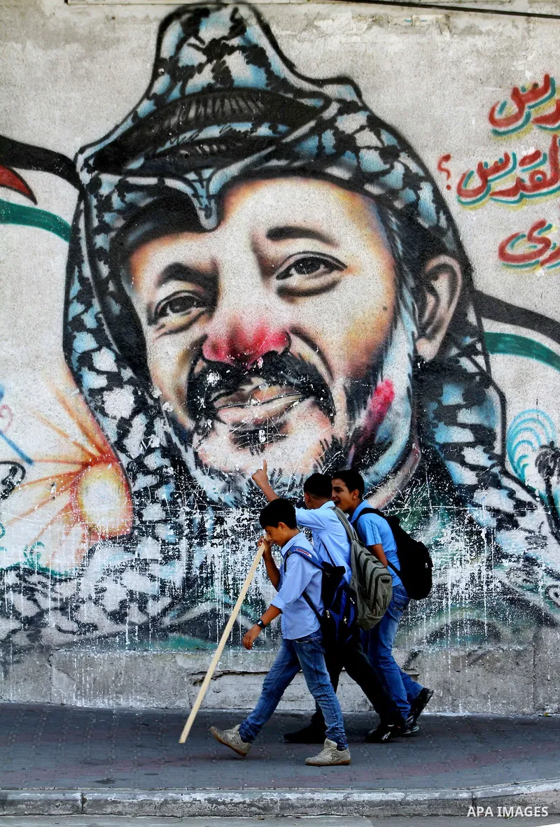 Palestinian school children walk in front of a mural painting of late Palestinian leader Yasser Arafat in central Gaza City on Sep. 17, 2011. The Palestinians are preparing to submit a formal request to become the 194th...