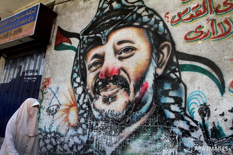 Palestinian woman walks in front of a mural painting of late Palestinian leader Yasser Arafat in central Gaza City on Sep. 17, 2011. The Palestinians are preparing to submit a formal request to become the 194th member of...