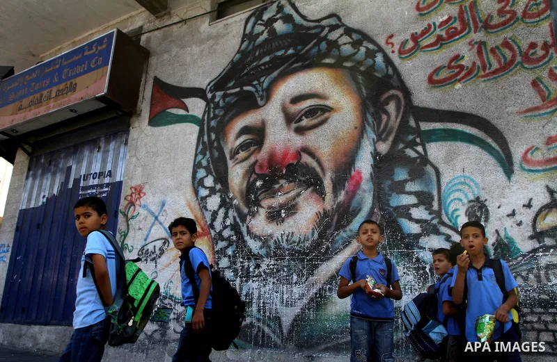 Palestinian students stand in front of a mural painting of late Palestinian leader Yasser Arafat in central Gaza City on Sep. 17, 2011. The Palestinians are preparing to submit a formal request to become the 194th member...