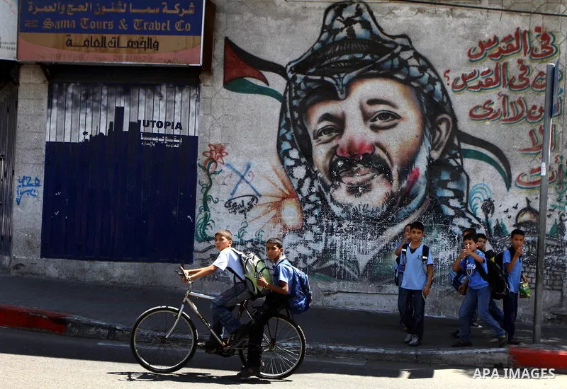 Palestinian students stand in front of a mural painting of late Palestinian leader Yasser Arafat in central Gaza City on Sep. 17, 2011. The Palestinians are preparing to submit a formal request to become the 194th member...