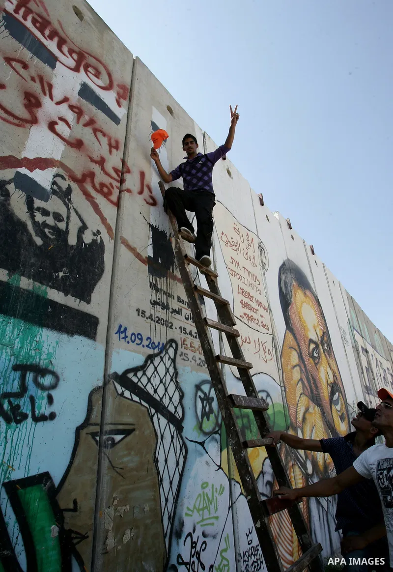 A Palestinian man waves Palestinian flags next to a mural during a demonstration calling for a Palestinian state with full UN membershipat in Jerusalem, on 17 September 2011. Palestine is set to submit a formal request t...