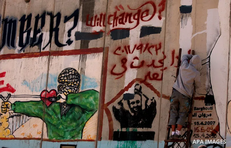 Foreign activist paints graffiti on a separation barrier during a protest calling for a Palestinian state with full UN membership at the Qalandia checkpoint between the West Bank city of Ramallah and Jerusalem, Saturday,...