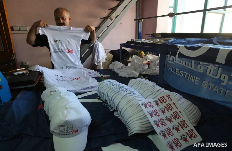 Palestinian man folds t-shirts bearing a symbolic emblem of a proposed future Palestinian state at a work shop in the West Bank city of Nablus .Saturday,Sept. 17, 2011. Palestinian President Mahmoud Abbas is set to addre...