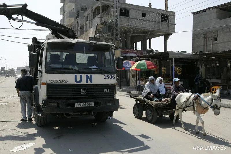 A Palestinian rides his donkey cart past a UN truck collecting garbage on September 18, 2011, at refugee camp in the southern Gaza Strip. The Palestinians are preparing to submit a formal request to become the 194th memb...