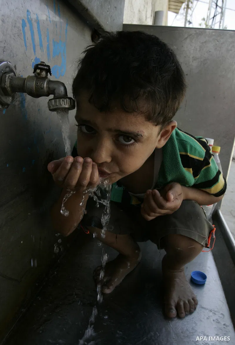 Palestinian children fill bottles from a public water tap at the United Nations Relief and Works Agency (UNRWA) headquarters, in Rafah refugee camp in the southern Gaza strip on September 18, 2011. The Palestinians are p...