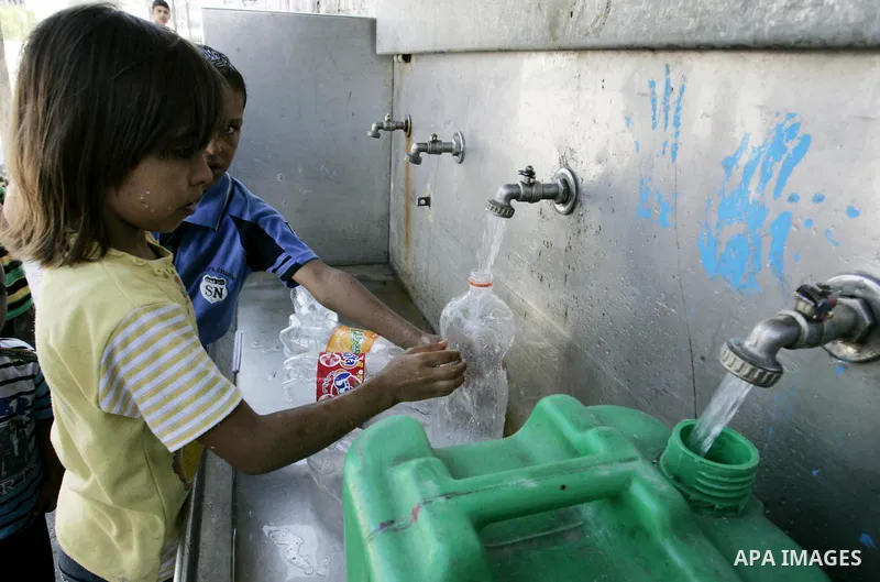 Palestinian children fill bottles from a public water tap at the United Nations Relief and Works Agency (UNRWA) headquarters, in Rafah refugee camp in the southern Gaza strip on September 18, 2011. The Palestinians are p...