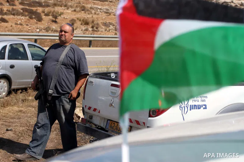 An armed Israeli settler from the Halamish settlement looks at members of pro-Palestinian volunteer-based campaign which will intervene and respond to cases of violence towards Palestinians by Jewish settlers in the West...