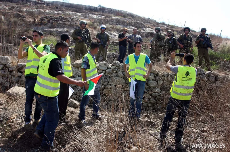 Israeli soldiers stand guard in front of members pro-Palestinian volunteer-based campaign which will intervene and respond to cases of violence towards Palestinians by Jewish settlers in the West Bank, in the West Bank v...