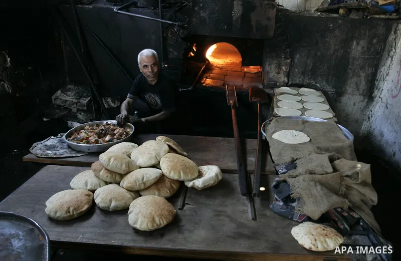 A Palestinian man bakes bread in a traditional mud oven in Rafah refugee camp, southern Gaza Strip on September 19, 2011. A diplomatic showdown looms at the United Nations this month when Palestinian President Mahmoud Ab...