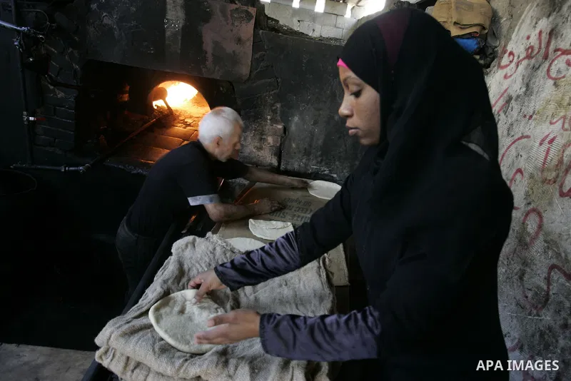 A Palestinian man bakes bread in a traditional mud oven in Rafah refugee camp, southern Gaza Strip on September 19, 2011. A diplomatic showdown looms at the United Nations this month when Palestinian President Mahmoud Ab...
